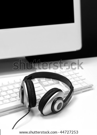 A desktop computer with a set of headphones isolated against a white background