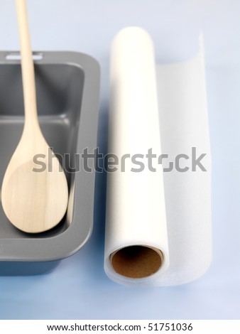 A cake tin and cooking utensils isolated against a blue background