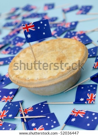 An Australian meat pie isolated against a blue background with Australian flags