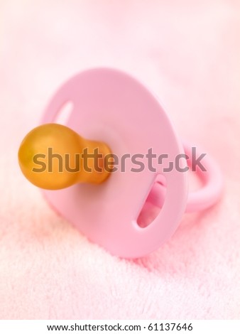 A pink pacifier isolated against a pink background