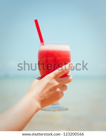 Woman holding fresh fruit cocktail on a tropical island beach