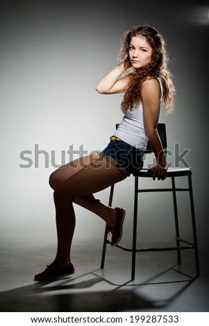 Portrait of young pretty woman sitting  on chair in studio