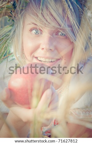 Image of young wondering woman on wheat field with apple