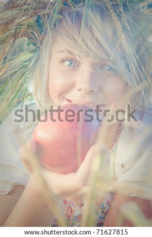 Image of young wondering woman on wheat field with apple