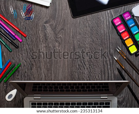 Office tools assortment and laptop frame background on dark table