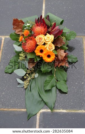 Arrangement with fresh flowers and green leaves for cemetery or funeral