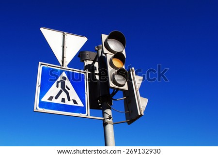 Yellow traffic light and pedestrian crossing sign