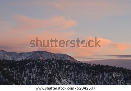 sun setting in the san bernardino mountains on the way down from big bear lake,with colorful clouds surrounding the snowy mountain peaks,california,december 2009.