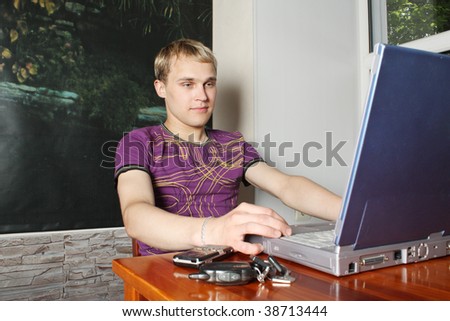 The young man works on the laptop behind a cafe table