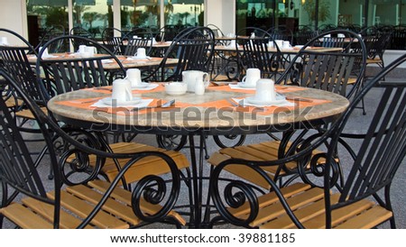 Tables with chairs, laid for coffee or tea, in an outside area