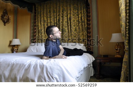 Young man leaning on a canopy bed