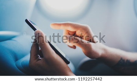 Cropped image of male hands using modern smartphone in aircraft, businessman typing text message during flight, business travel, man working in airplane on cellphone, cover page template for website