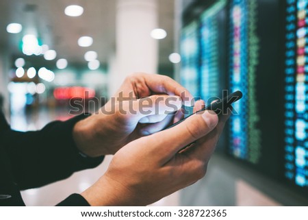 Businessman using smartphone and checking flight information at airport