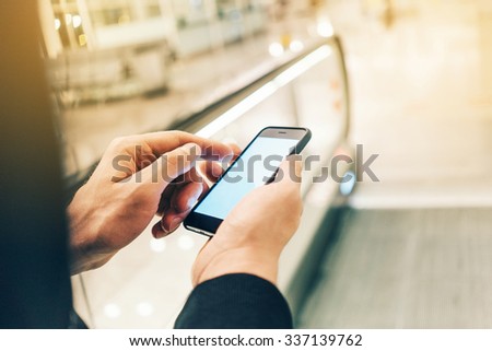 Businessman using smartphone on the escalator, with flare effect