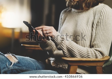 Close-up image of hipster girl sitting at vintage cafe and using modern smarphone, female hands typing message on mobile phone in home interior