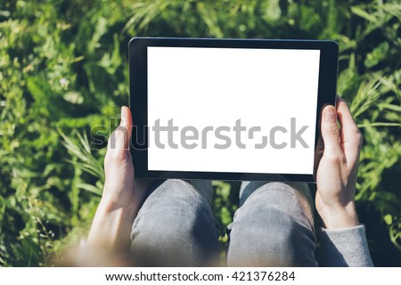 Close-up of female hands showing and using modern digital tablet with blank screen for your text message, mock-up of template tablet pc, hipster girl sitting at the park with technology outside