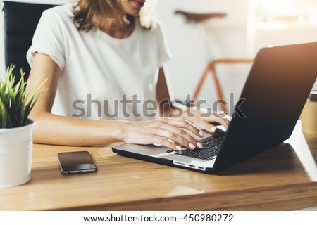 Close-up image of young professional female manager using laptop at her office, businesswoman working from home via portable computer, hipster girl freelancer writing on keyboard, flare light