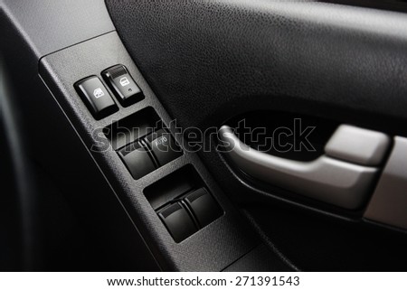 Car door interior arm rest with window control panel, door lock button, and mirror control.