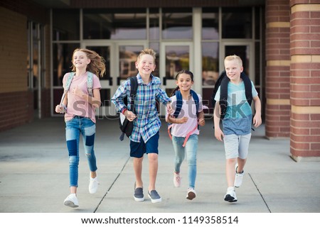 Group of school kids running as they leave elementary school at the end of day. Going home from school happy and excited. Back to school photo