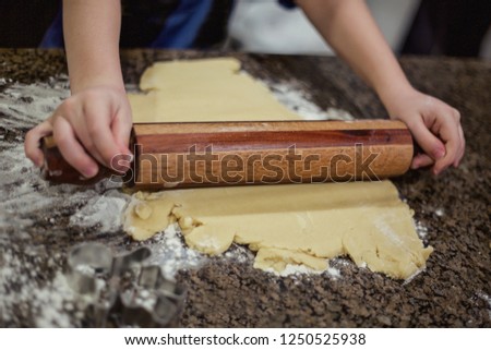 Preparing Christmas cookie dough using a rolling pin to prepare the dough. Selective focus on rolling the sugar cookie dough on the marble countertop