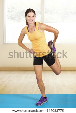 Fit muscular woman stretching before her workout. Indoor fitness class