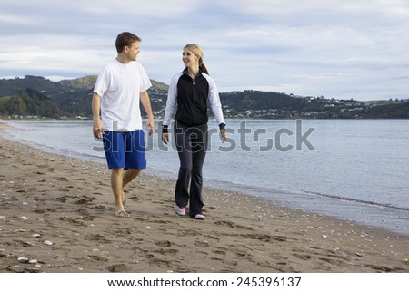 Two friends talking and walking along beach together