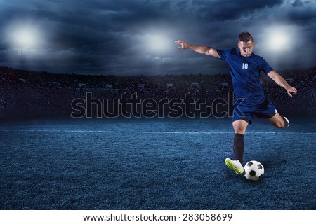 Professional soccer or football player during game in full floodlit stadium at night