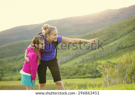 Family hiking in the mountains together. Young mother pointing out wildlife while she and her daughter take a hike together in the mountains on a beautiful summer evening