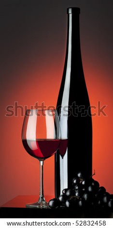 bottle and glass of wine with grapes on a red background