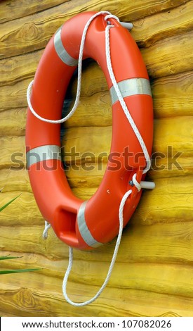 red life buoy hanging on a yellow wooden wall