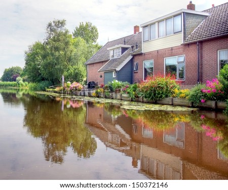 river / canal   in the Netherlands with houses on the waterside which are  giving a beautiful reflection on the water surface