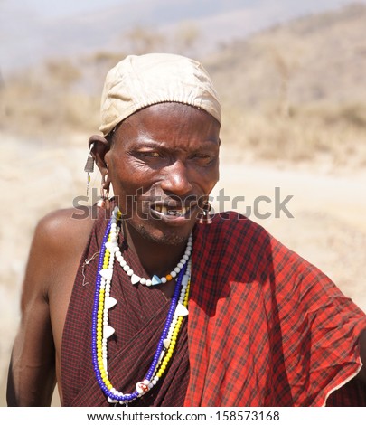 SERENGETI, TANZANIA - JULI 16, 2013: Unidentified male Maasai is posing for the camera at the Serengeti  on juli 16, Tanzania. Maasai are semi-nomadic people located in Kenya and northern Tanzania