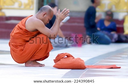 YANGON, MYANMAR - NOV 15: An unidentified buddhist monk kneels down in prayer on Nov 15, 2011 in Yangon, Myanmar