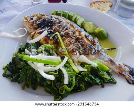 Grilled sea bream plate drizzled with olive oil accompanied by zucchini, spinach and chopped onion and pepper.