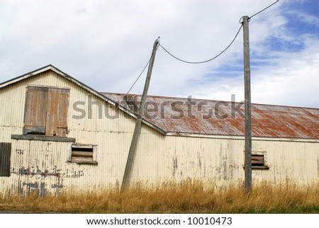 A delapidated, rusty barn on a sheep farm in New Zealand