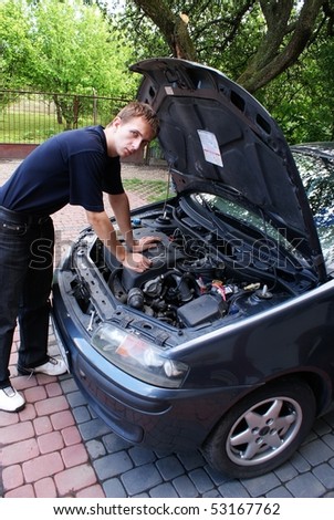 This is a car mechanic next to the engine of small city car
