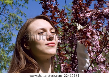 Portrait of young woman with butterfly on blossom tree background
