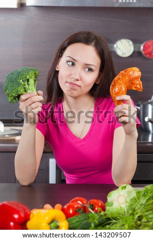 Young woman has a problem of choice - is meat or vegetables