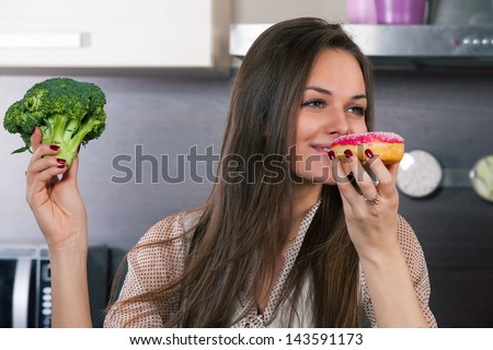 Young woman chooses what to eat vegetables or a cake