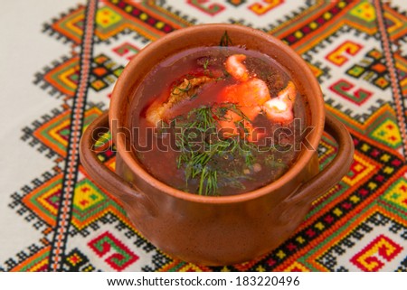 Ukrainian borsch in a ceramic pot on embroidered towel