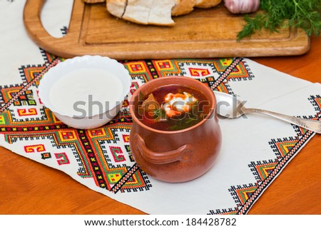 Ukrainian borsch and a bowl of sour cream on embroidered towel