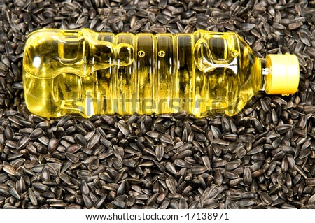 Plastic bottle with sunflower-seed oil against sunflower seeds.