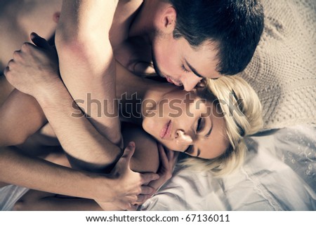 Young couple hugging on the bed in bedroom - stock photo