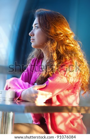 Beautiful red-haired girl in a cafe drinking tea
