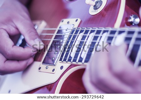 Hands of man playing electric guitar. Low key photo.