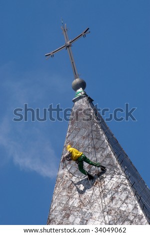 Climber on a dome of the church, carrying out works under pressure washing a roof