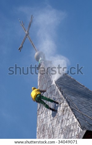 Climber on a dome of the church, carrying out works under pressure washing a roof
