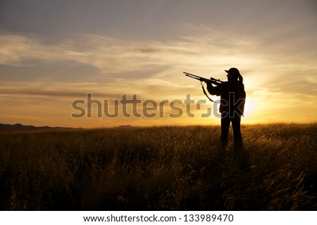 Woman Rifle Hunter Silhouetted at Sunset