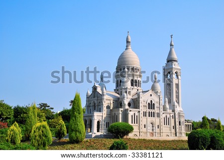 White, European style church architecture surrounded with nature with bird perched on roof