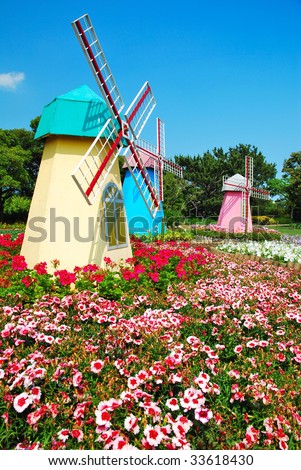 Model of three holland windmills in a park with field of flowers